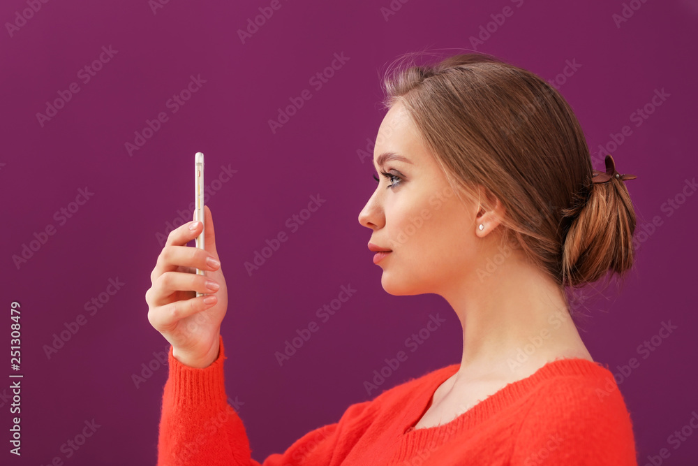 Obraz premium Young woman taking selfie with mobile phone on color background