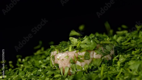 Raw pork meat with chopped parsley on black background in slowmotion. photo