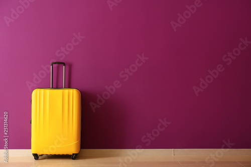 Packed suitcase near color wall