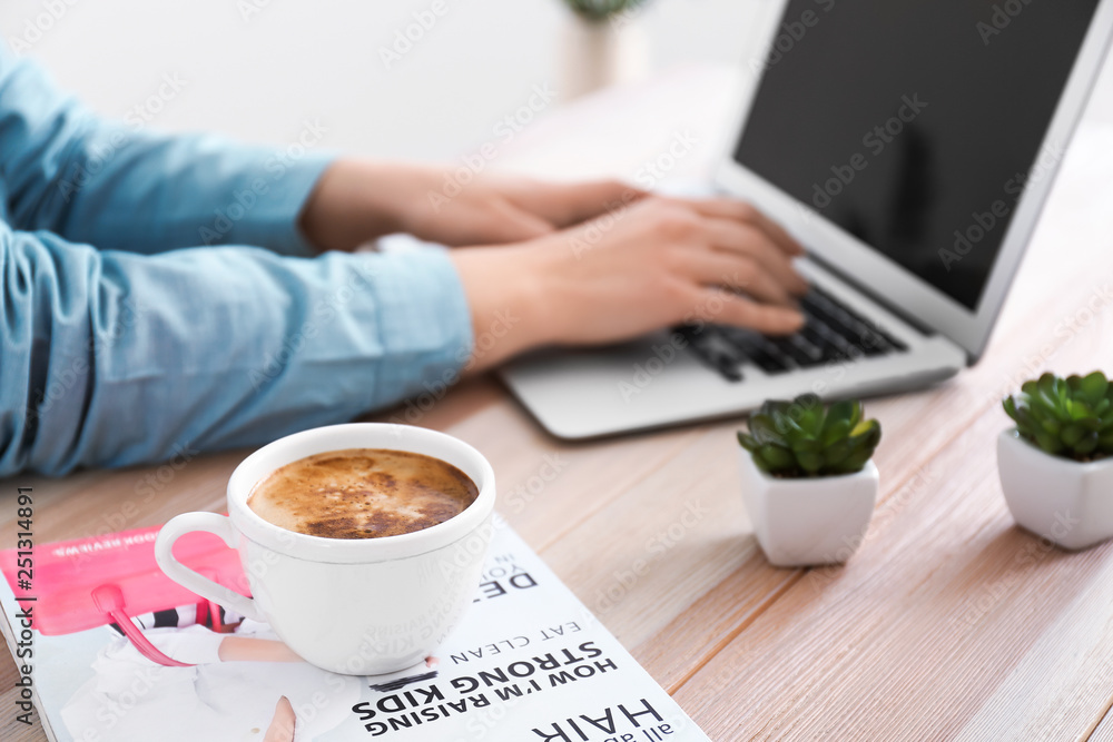 Cup of coffee on table of woman working with laptop Cup of coffee on table of woman working with laptop