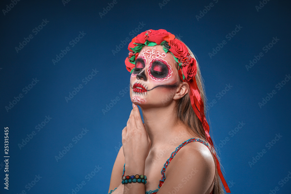 Fototapeta premium Young woman with painted skull on her face for Mexico's Day of the Dead against color background