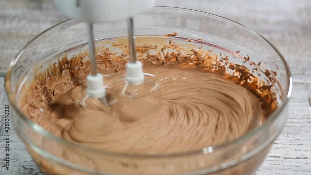 Confectioner beating chocolate cream with a hand mixer. Cooking chocolate cream on kitchen. Confectioner beating chocolate cream with a hand mixer. Cooking chocolate cream on kitchen.
