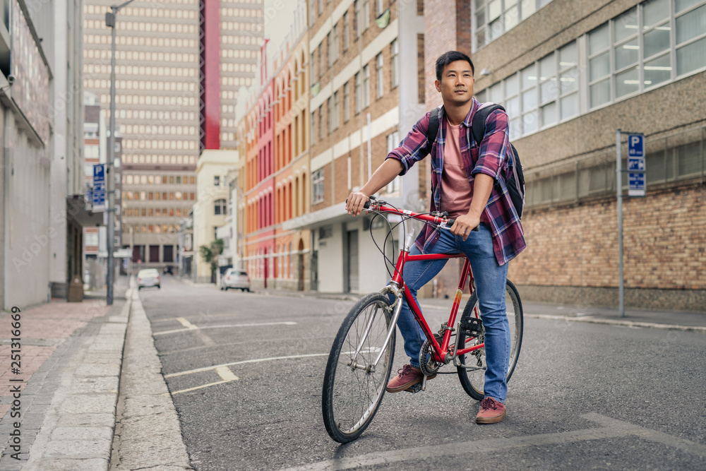 Young man sitting on his bicycle on a city street