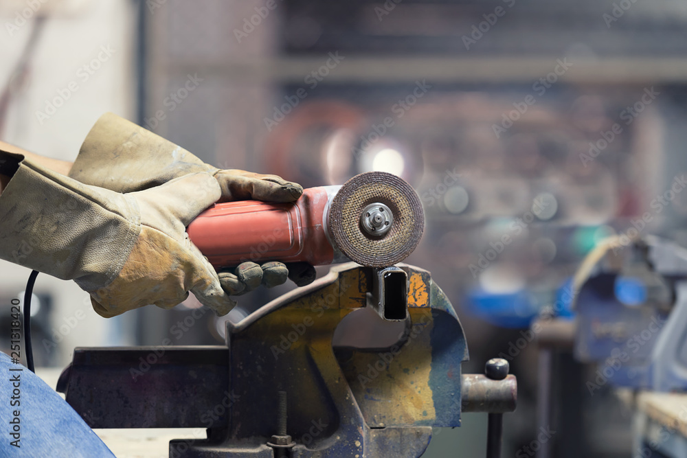 Hands of Engineer cutting steel pipe with sparking cutter.