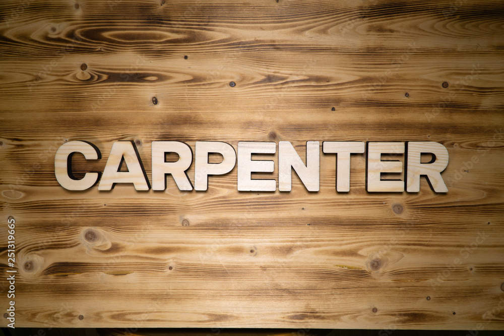 CARPENTER word made of wooden block letters on wooden board, top view.