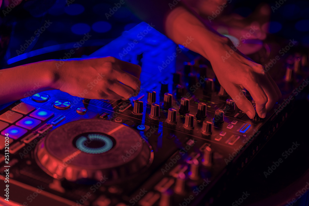 Close up, DJ mixing tracks on a mixer in a nightclub. Close up, DJ mixing tracks on a mixer in a nightclub.