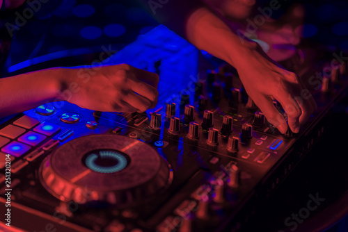 Close up, DJ mixing tracks on a mixer in a nightclub.