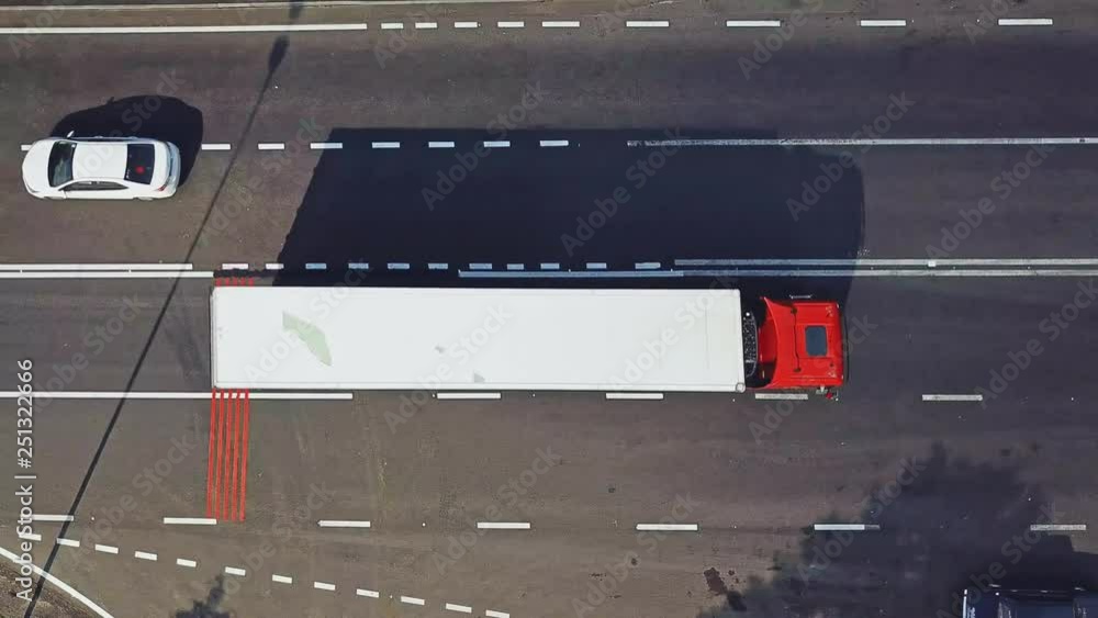 Few long vertical red stripes painted on one side of the road surface and cars passing. Aerial view of wide asphalt road divided into two opposite sides for cars. Camera moves right Few long vertical red stripes painted on one side of the road surface and cars passing. Aerial view of wide asphalt road divided into two opposite sides for cars. Camera moves right