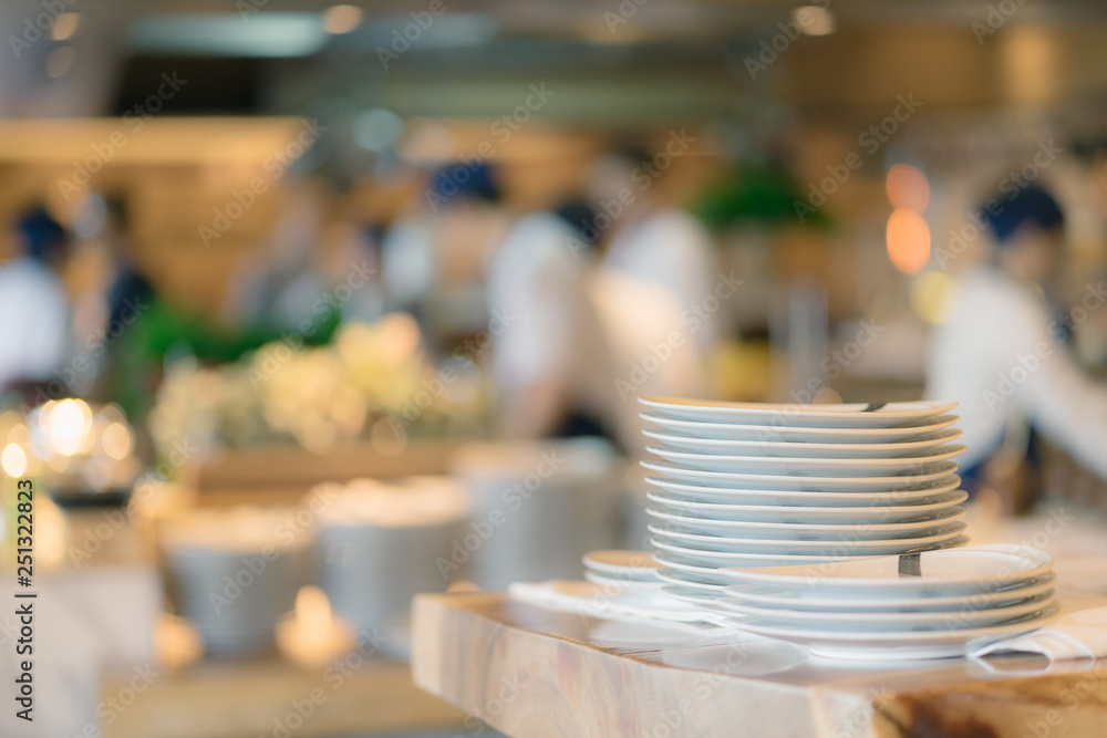 Stack of plate on counter and blurred background. Groups of Chef preparation counter of food in the open kitchen, International foods buffet. Stack of plate on counter and blurred background. Groups of Chef preparation counter of food in the open kitchen, International foods buffet.