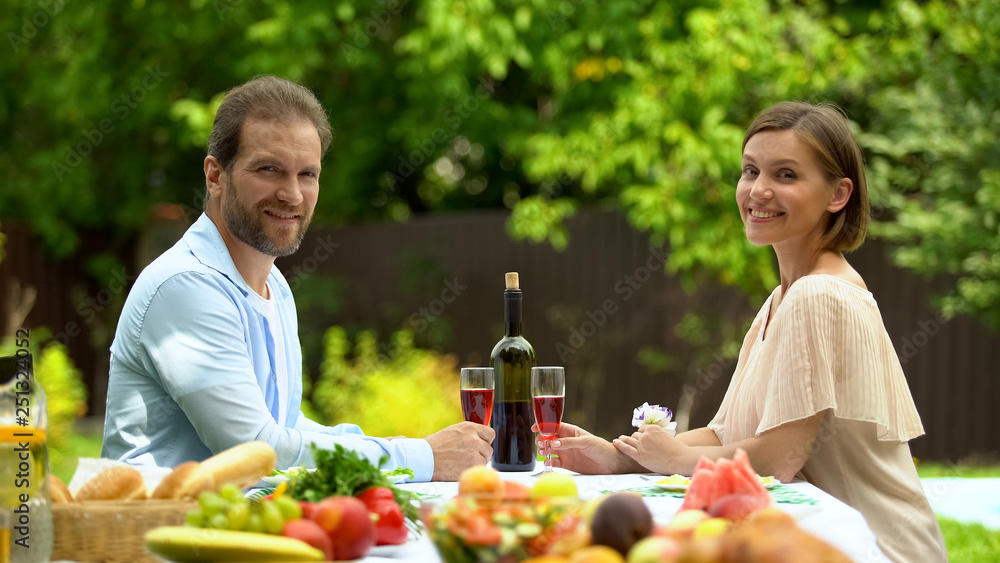Cheerful couple holding wine glasses and looking at camera, healthy lifestyle