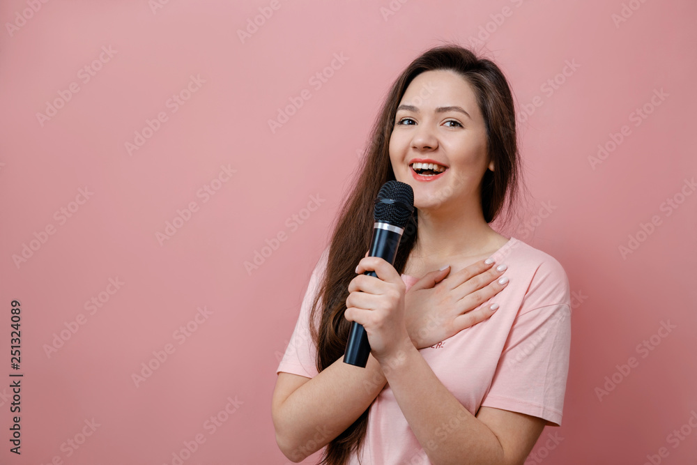 young smilling woman with microphone in hand on pink background young smilling woman with microphone in hand on pink background