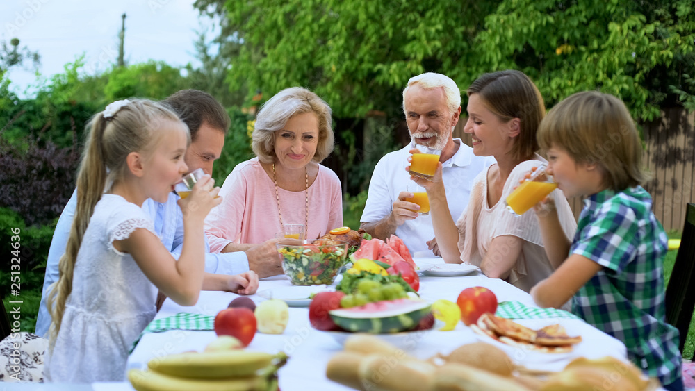 Healthy cheerful family drinking vitaminized fresh juice, celebrating traditions Healthy cheerful family drinking vitaminized fresh juice, celebrating traditions