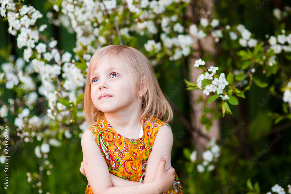 cute little girl near blooming apple trees and cherry