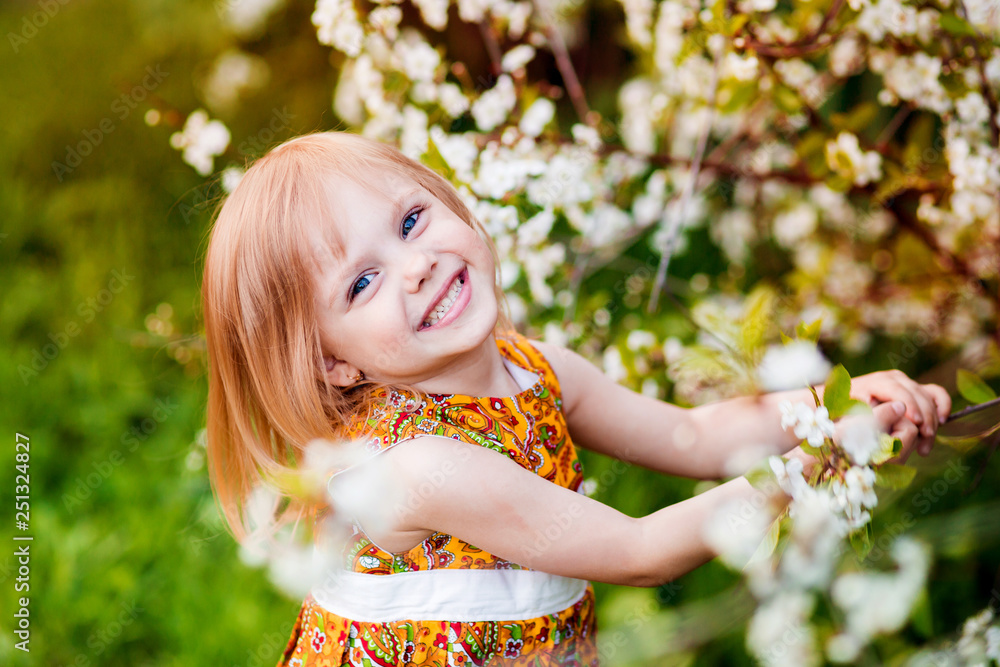 Fototapeta premium cute little girl near blooming apple trees and cherry