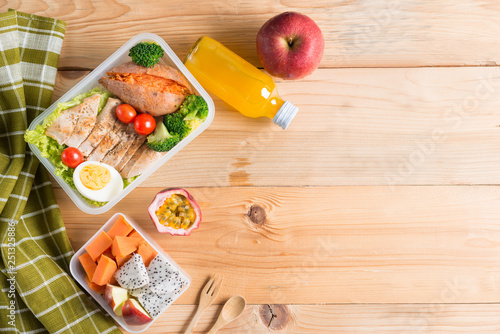 Healthy lunch boxes in plastic package, Grilled chicken breast with sweet potato, egg and vegetable salad, fruit, orange juice. Diet food concept. Top view and Copy space.