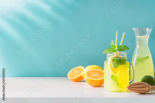 Lemonade in mason jar with lemon and mint on blue. Copy space.