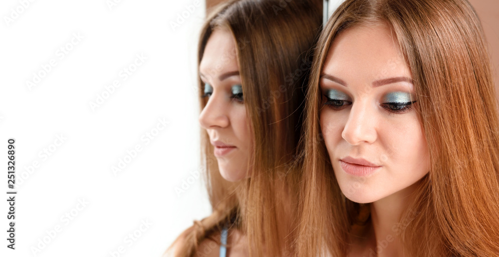 Portrait of a beautiful young woman with long hair near the mirror Portrait of a beautiful young woman with long hair near the mirror