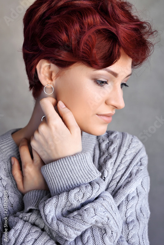 Portrait of a beautiful young red-haired woman with short hair wearing warm woolen sweater