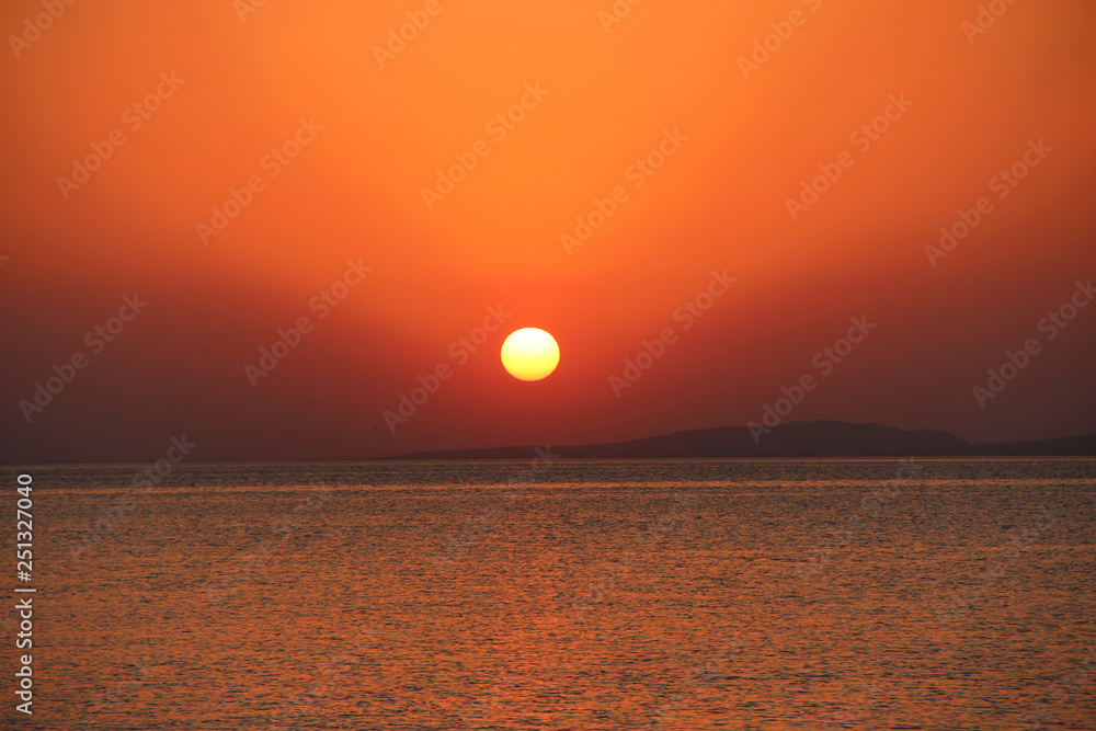 Sunset above sea. Red sun raising above ocean in early morning