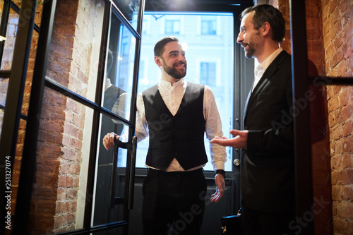 Schilderij op canvas Front view portrait of two handsome gentlemen entering cafe chatting cheerfully,