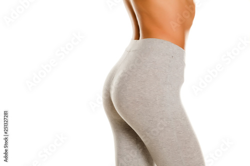 sexy slim female buttocks in gray leggingss on white background