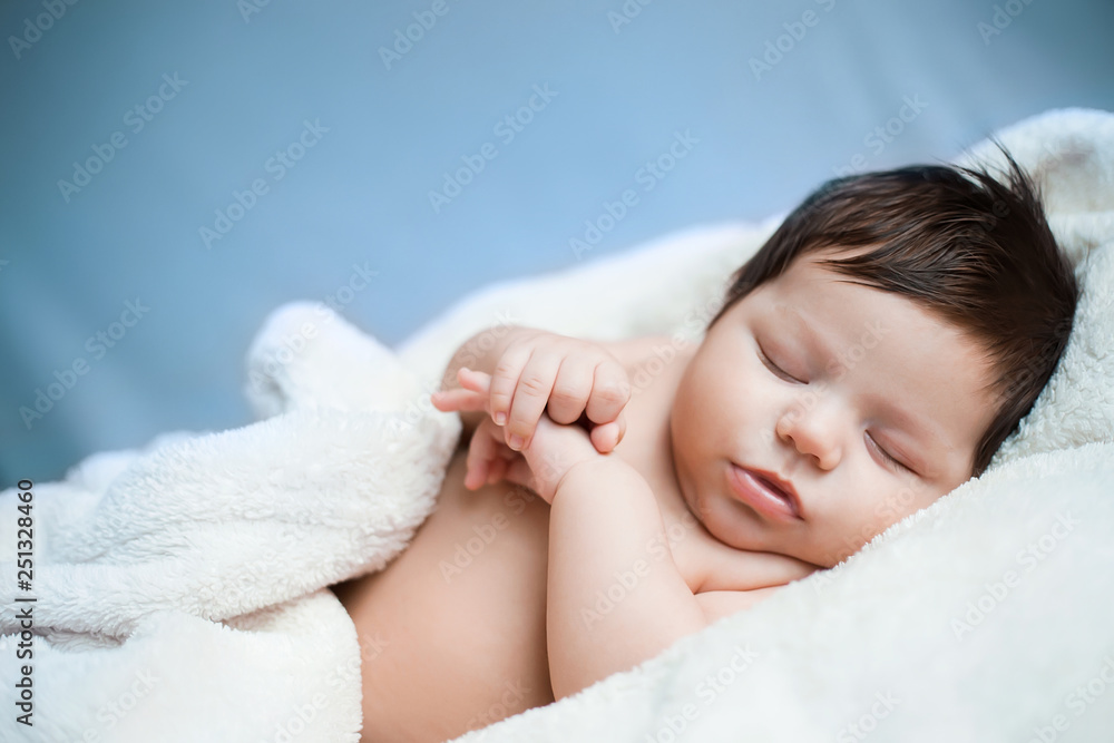 newborn baby sleeps on a blue background, dark-haired newborn baby sleeps on a blue background, dark-haired