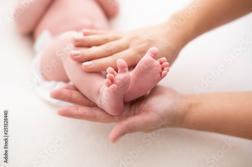 Baby feet cupped into mothers hands. Gentle blurred background of the feet and heels of a newborn