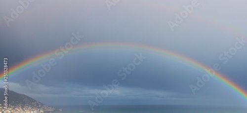 Rainbow over the sea  dark rainy sky