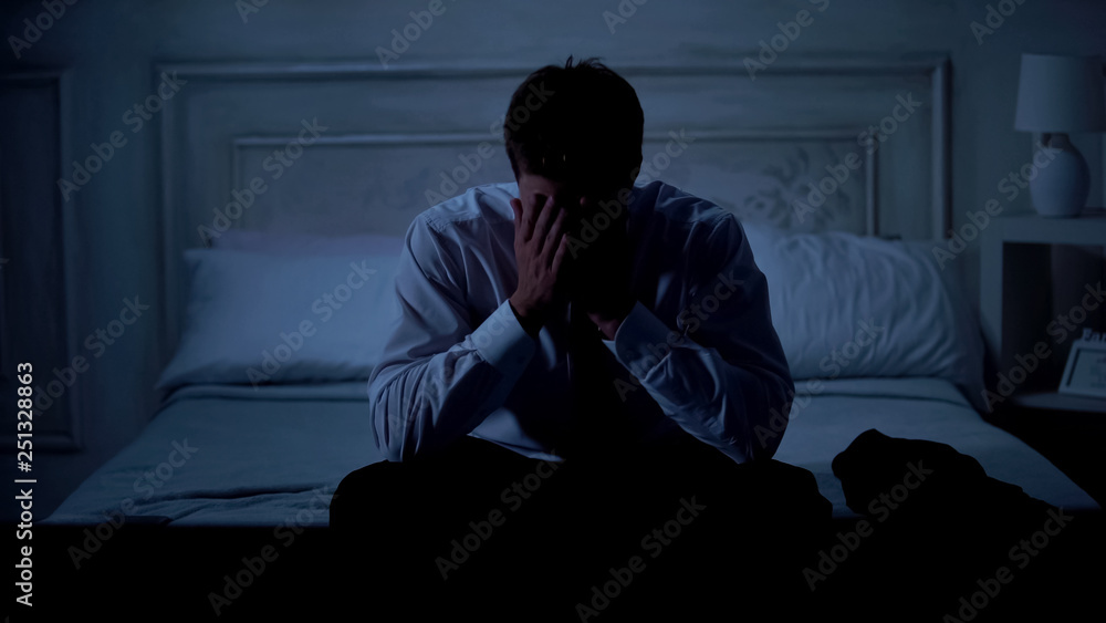 Fototapeta premium Disappointed businessman sitting on bed at home, startup failure, problems