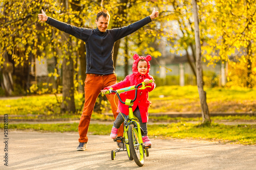 Fototapeta Naklejka Na Ścianę i Meble -  Father teaching daughter ride bike in park