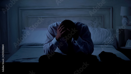 Unhappy businessman sitting on bed, project failure, unemployment and bankruptcy © motortion