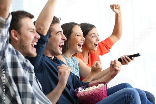 Excited friends watching tv celebrating success