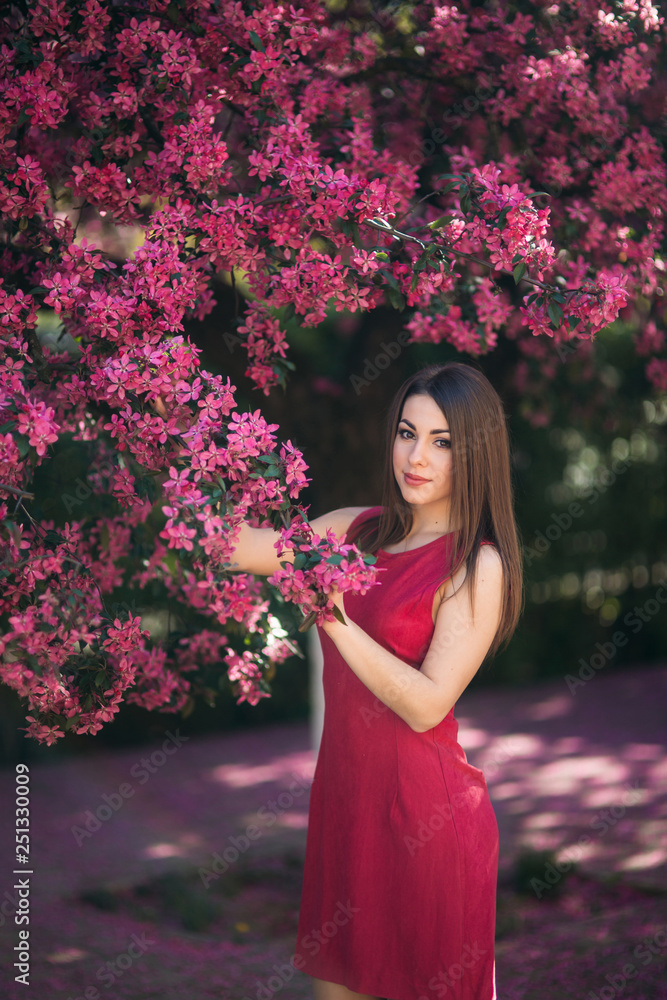 Beautiful lady stand by the big blooming tree voilet color. Happy girl with makeup in spring Beautiful lady stand by the big blooming tree voilet color. Happy girl with makeup in spring
