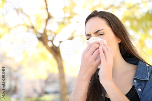 Sick woman sneezing covering nose in a park