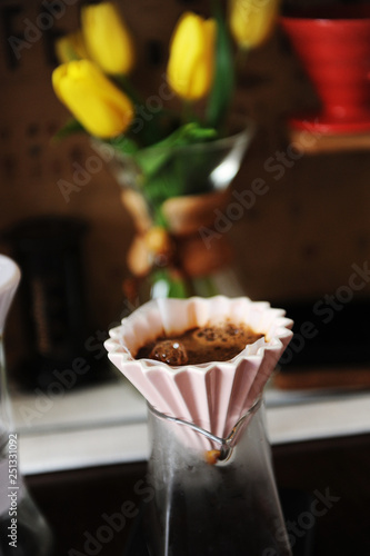 Alternative coffee brewing in pink ceramic dripper with paper filter. Yellow flowers tulips on the background photo