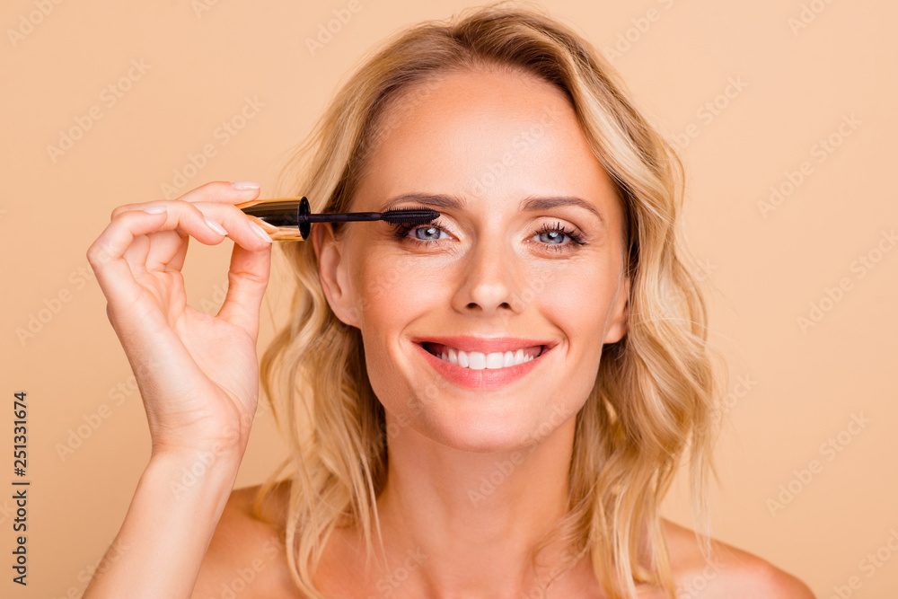 Close-up portrait of trendy modern nice cheery wavy-haired lady with perfect pure clean clear fresh smooth flawless shine skin applying mascara brush on eye lashes isolated on beige background