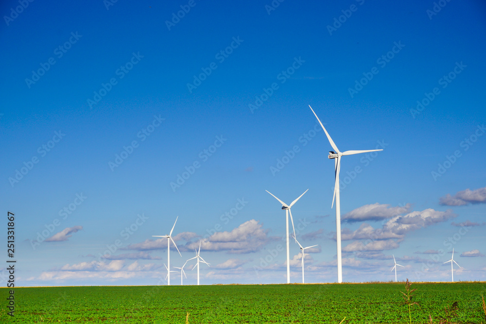 wind power plant consisting of several wind turbines standing in a field against a blue sky wind power plant consisting of several wind turbines standing in a field against a blue sky