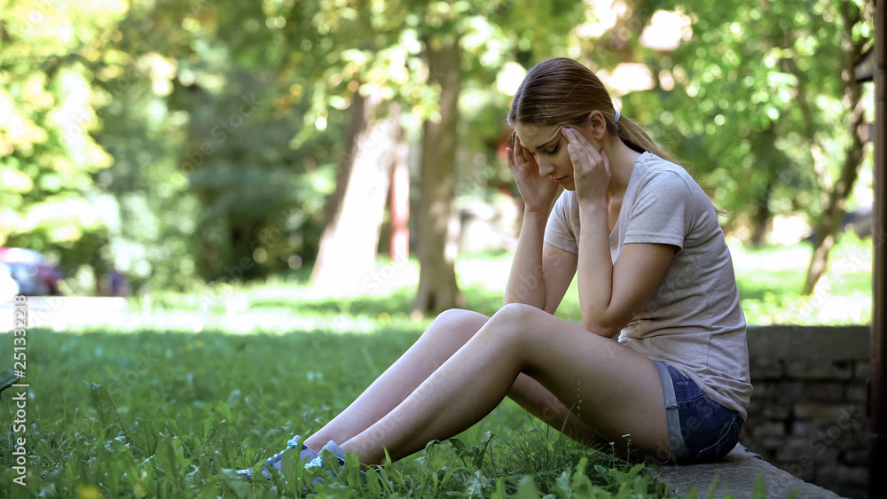 Woman having migraine, sitting alone in park, needs ambulance, chronic fatigue Woman having migraine, sitting alone in park, needs ambulance, chronic fatigue
