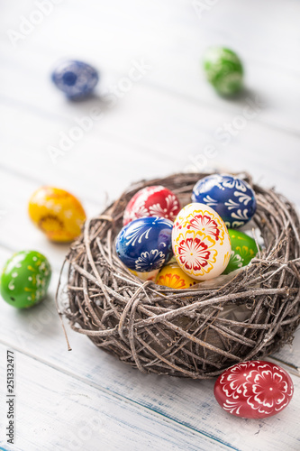 Close-up multicolored easter eggs in basket on wooden table