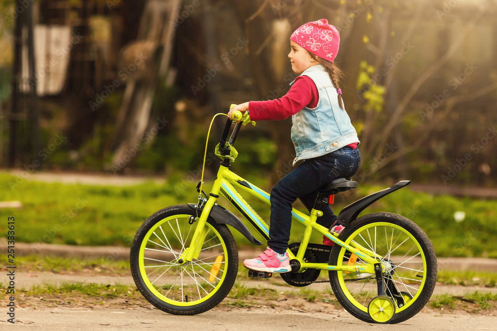 Beautiful smiling little girl riding bicycle in a park