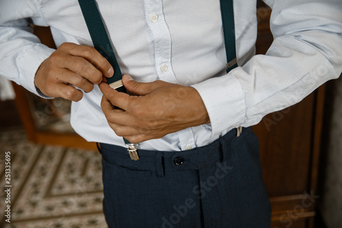 A man is adjusting his suspenders closeup.