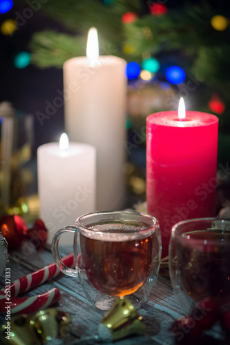 A couple of burning candles and glass cups of tea. Still life composition with christmass decoration on rustic background 3