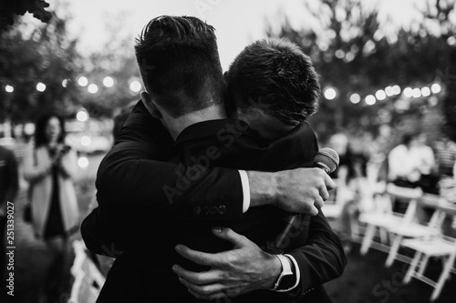A groom is hugging with a best man. Farewell hug concept. photo