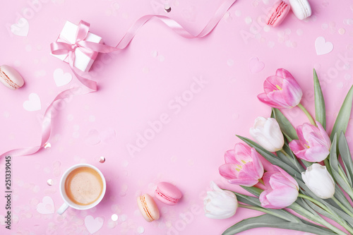 Morning cup of coffee, cake macaron, gift or present box and spring tulip flowers on pink background. Beautiful breakfast for Women day, Mother day. Flat lay.