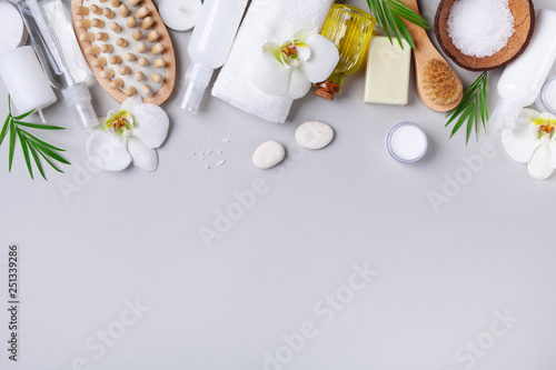 Spa, aromatherapy, beauty treatment and wellness background with massage brush, towel, orchid flowers and cosmetic products. Top view and flat lay.