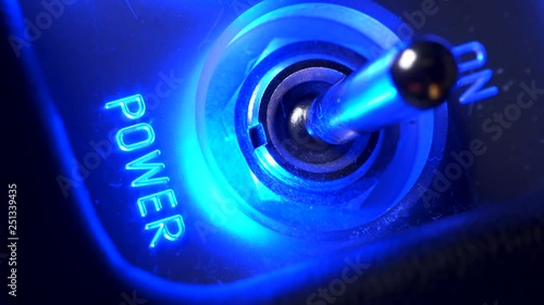 Male finger turning control switch on and power flashing blue lights close-up. Small lever metal toggle professional modern equipment adjusting voltage top view high angle