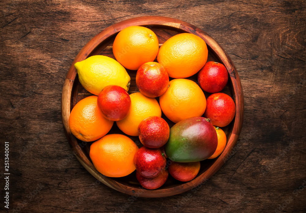 Bright fruits in large tray: oranges, lemons, mango in assortment. View from above