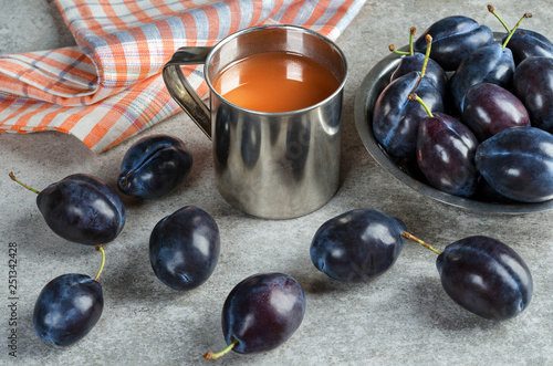 Plum juice in a mug and ripe plums.