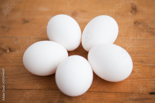 Five white eggs on a wood ground