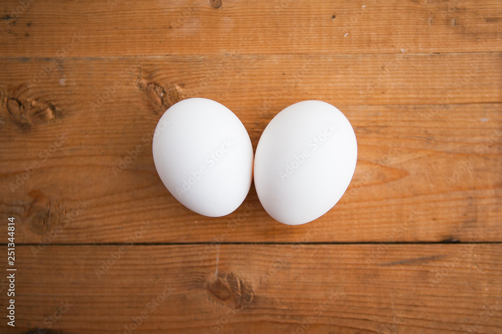 Two white eggs on a wood ground